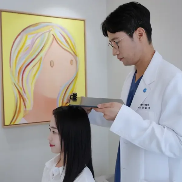 신사역 여자 헤어라인 — 의료진이 헤어라인을 측정하며 상담하는 실제 사진