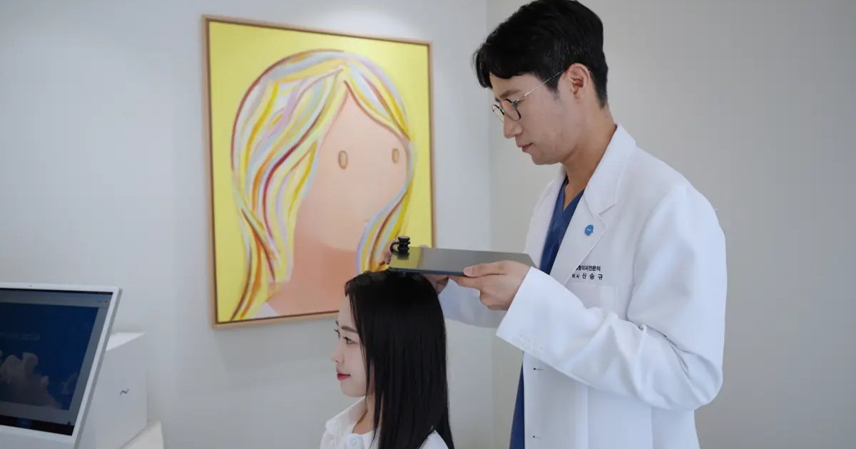 신사역 여자 헤어라인 — 의료진이 헤어라인을 측정하며 상담하는 실제 사진